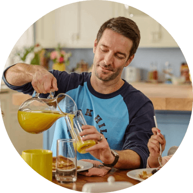 man pouring glass of orange juice